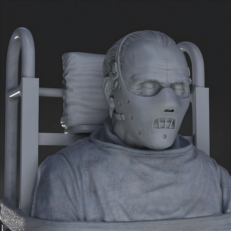 May include: A gray sculpture of a person wearing a face mask and a gray smock, seated in a chair with a headrest. The mask has multiple holes and a mouth guard. The sculpture has detailed facial features and is set against a dark background.