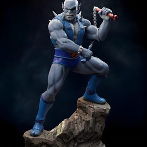 Puede incluir: Estatua detallada de una figura humanoide musculosa de piel gris en una pose din&aacute;mica. La figura lleva pantalones cortos azules, botas y un chaleco con p&uacute;as plateadas. Sostiene un arma de cadena con mangos rojos, de pie sobre una base rocosa.