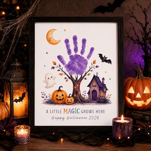 Può includere: Una stampa incorniciata con un'impronta di mano viola come chioma di un albero, circondata da una luna crescente sorridente, un fantasma, un pipistrello, due zucche e una casetta. Il testo recita: A LITTLE MAGIC GROWS HERE Happy Halloween 2026.