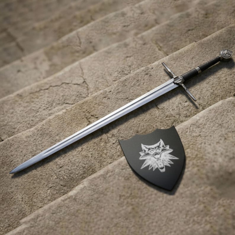 May include: A silver sword with a black handle and crossguard lies on stone steps beside a black shield. The shield displays a white wolf emblem. The sword has a long, straight blade.