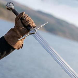 May include: A set of three ceramic mugs with a speckled, matte finish in cream, light grey, and dark grey. Each mug has a simple, minimalist design and a rounded handle.