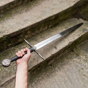 May include: A trio of cream-glazed ceramic mugs, each adorned with a hand-painted floral pattern in blue, green, and yellow. The mugs have a speckled finish and a classic, rounded design with a handle. Ideal for tea or coffee.