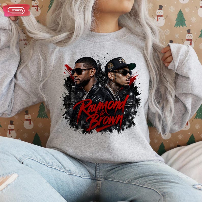 Digital bootleg rap tee graphic featuring R&B artists Usher and Chris Brown standing back-to-back wearing sunglasses and black jackets. The background showcases a high-contrast nighttime city skyline with glowing lights, abstract geometric stars, and bold red brushstroke text reading "Raymond & Brown".