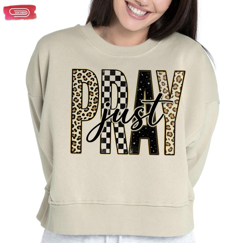 Bold "PRAY" text with leopard, checkerboard, and starry patterns, overlaid with a cursive "just" script, featuring a gold outline.