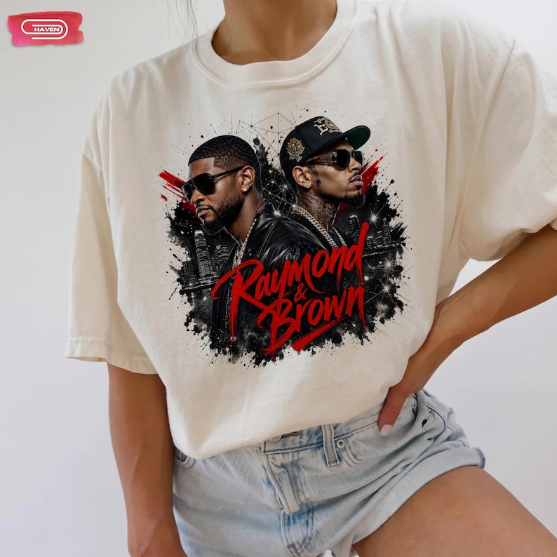 Digital bootleg rap tee graphic featuring R&B artists Usher and Chris Brown standing back-to-back wearing sunglasses and black jackets. The background showcases a high-contrast nighttime city skyline with glowing lights, abstract geometric stars, and bold red brushstroke text reading "Raymond & Brown".