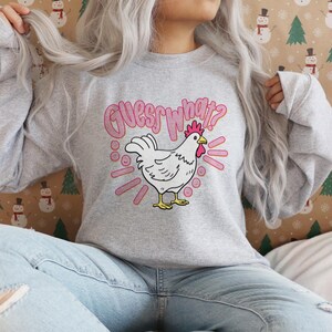 Lifestyle mockup of a preppy girl wearing a white oversized t-shirt featuring the funny pink Guess What Chicken Butt matching front and back sublimation designs.