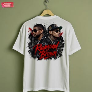 Digital bootleg rap tee graphic featuring R&B artists Usher and Chris Brown standing back-to-back wearing sunglasses and black jackets. The background showcases a high-contrast nighttime city skyline with glowing lights, abstract geometric stars, and bold red brushstroke text reading "Raymond & Brown".