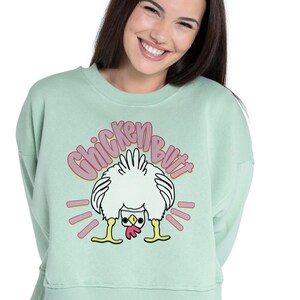 Lifestyle mockup of a preppy girl wearing a white oversized t-shirt featuring the funny pink Guess What Chicken Butt matching front and back sublimation designs.