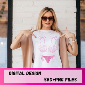 May include: A white t-shirt featuring a pink graphic design of a bikini set. The design includes two bows at the top, two seashell-shaped cups in the middle, and a pair of striped bikini bottoms with side ties at the bottom of the shirt graphic.