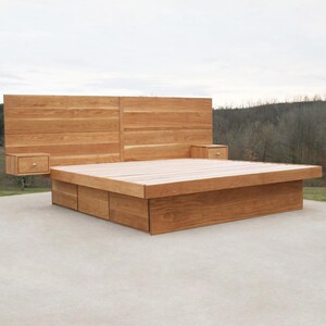 May include: A modern wooden bed frame with a headboard and two floating nightstands. The bed frame is made of light brown wood and has a platform base with storage drawers. The headboard is a large, rectangular panel.