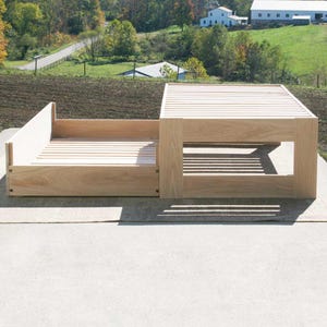 May include: A wooden platform bed frame with a slatted headboard and footboard. The frame is made of natural wood and has a simple, modern design.