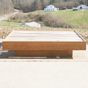 May include: A wooden platform bed frame with a slatted headboard. The frame is made of natural wood and has a simple, modern design.