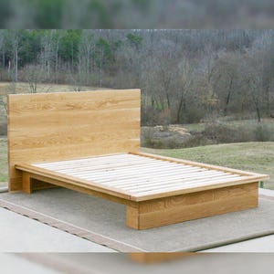 May include: A wooden platform bed frame with a slatted base and a headboard. The bed frame is made of natural wood and has a simple, modern design.