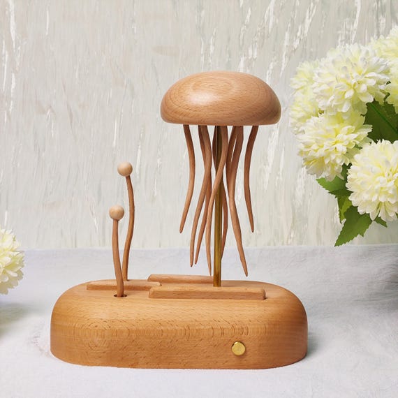 A hand-carved wooden jellyfish that undulates with hypnotic, lifelike motion via a crank mechanism — pure automata craft that looks alive on your desk.