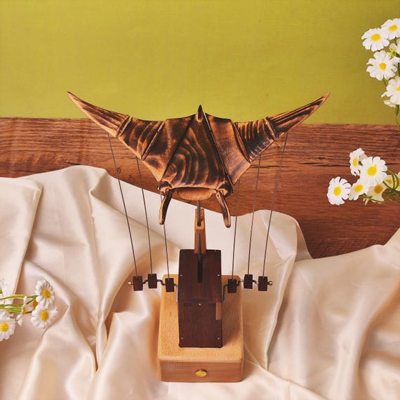 A hand-carved wooden manta ray that actually *swims* through the air via mechanical automaton linkage — pure kinetic magic you can put on a desk.