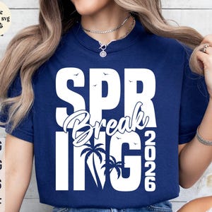 May include: Navy blue t-shirt with the words "SPRING BREAK 2026" in white, featuring palm trees and birds. The shirt also has the words "SVG, PNG, EPS, DXF" in white on the left side.