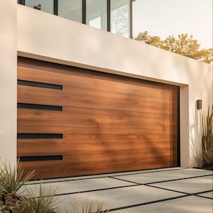 May include: A modern wooden garage door with horizontal planks and black rectangular accents. The door is a warm brown color, contrasting with the white exterior wall. The driveway is made of concrete with black lines.