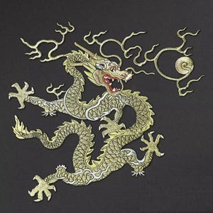 Peut inclure: Broderie d'un dragon doré sur fond noir. Le dragon présente des détails complexes, notamment des écailles, des griffes et une expression féroce. Le motif comprend des éléments tourbillonnants en forme de nuages. Le dragon est un symbole de pouvoir et de bonne fortune.