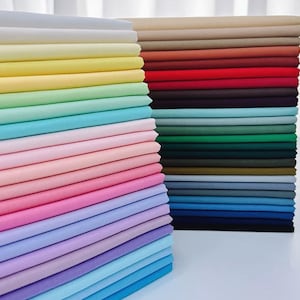 May include: Stacks of colorful fabric in a variety of shades, including yellow, green, pink, and blue. The fabric is neatly folded and stacked, creating a visually appealing display of textiles. The image showcases a range of colors, from light pastels to deeper hues.
