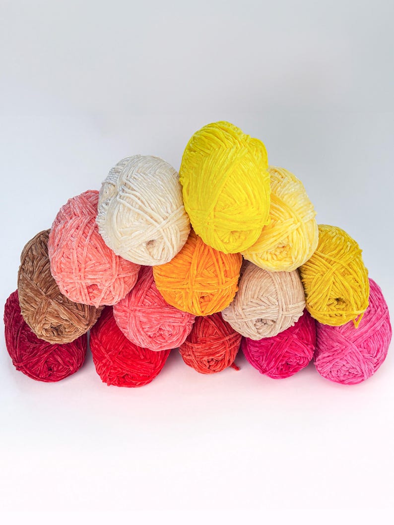 Puede incluir: Una colecci&oacute;n de ovillos de lana coloridos en tonos amarillos, rosas, rojos, naranjas, marrones y crema. Los ovillos de lana est&aacute;n apilados, creando una exhibici&oacute;n visualmente atractiva. Ideal para proyectos de tejido y ganchillo.