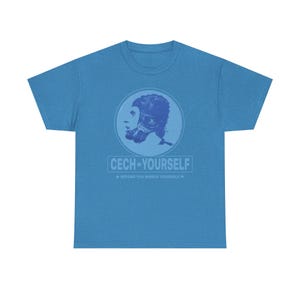 Peut inclure: T-shirt bleu clair avec un motif circulaire représentant une personne portant un casque d'aviateur vintage. Le texte "CECH YOURSELF" et "BEFORE YOU WRECK YOURSELF" est imprimé en dessous.
