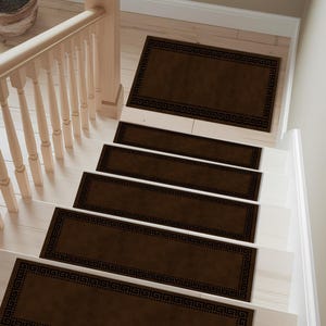 May include: Brown stair treads with a black Greek key border are installed on white stairs. The treads are rectangular and cover each step. A wooden banister and potted plant are visible in the background.