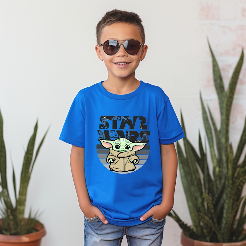 以下が含まれることがあります： スターウォーズのグローグのグラフィックが特徴の青いTシャツ。デザインには、グローグの上に「STAR WARS」という言葉が含まれています。サングラスをかけた子供がTシャツを着ています。