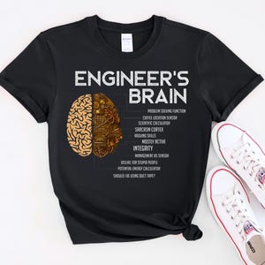 May include: Black t-shirt with the text "ENGINEER'S BRAIN" and a graphic of a brain split in two halves. One half is a brain, the other half is a circuit board. The shirt also lists the functions of an engineer's brain.