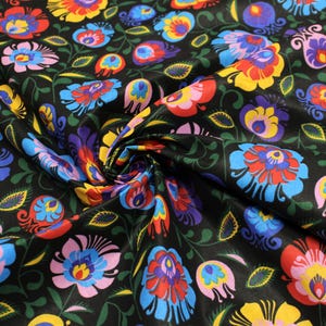 Può includere: Tessuto nero con un vivace motivo floreale. Il design presenta fiori colorati nei toni del rosso, blu, giallo e viola, con foglie verdi. Il tessuto è probabilmente utilizzato per abbigliamento o arredamento.