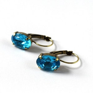 May include: A pair of blue gemstone earrings with antique gold-toned hoops.