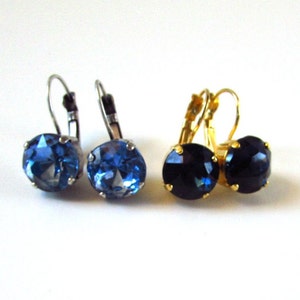 May include: Two pairs of earrings with blue gemstones. One pair has silver ear wires and a light blue gemstone. The other pair has gold ear wires and a dark blue gemstone.
