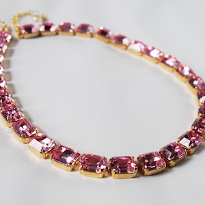May include: A gold chain necklace with pink rectangular-shaped crystals.