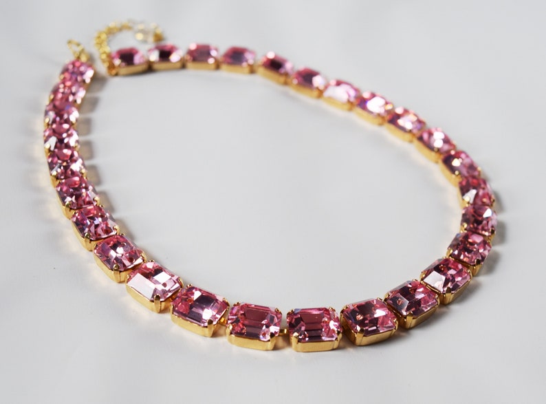 May include: A gold chain necklace with pink rectangular-shaped crystals.