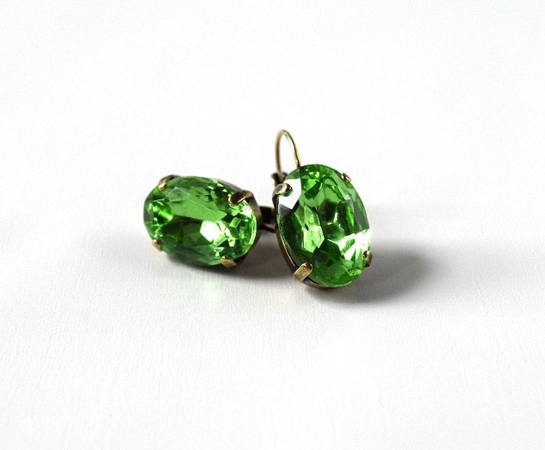 May include: A pair of green oval-shaped earrings with a gold-tone setting.