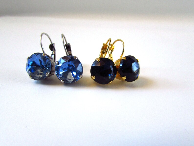 May include: A pair of earrings with blue and black crystal stones. The earrings have silver and gold-toned hooks.