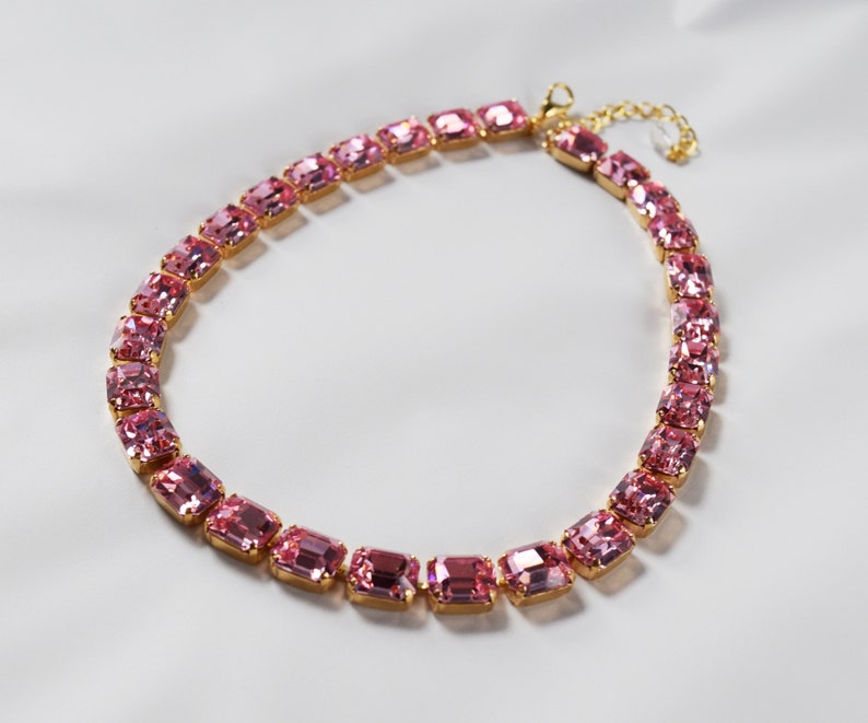 May include: A gold chain necklace with pink rectangular gemstones