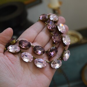 May include: A double-strand necklace with oval-shaped pink and purple glass beads. The necklace is made with antique brass findings.