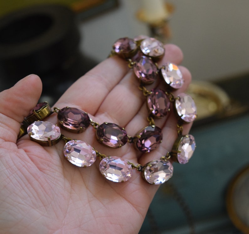 May include: A double-strand necklace with oval-shaped pink and purple glass beads. The necklace is made with antique brass findings.