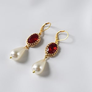 May include: A pair of gold earrings with red gemstone and white pearl drops.