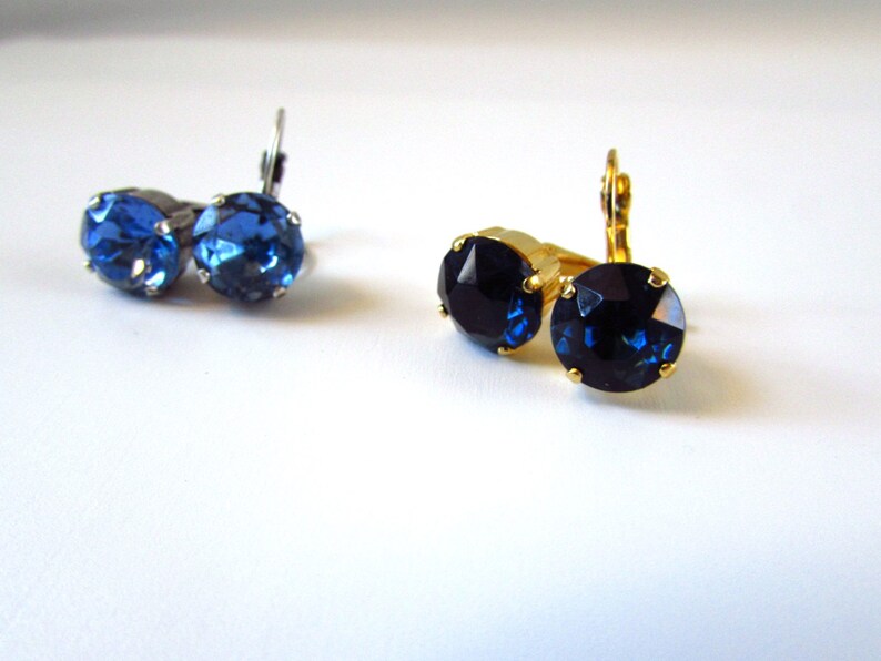 May include: Two pairs of earrings with blue rhinestones. One pair has silver settings and the other has gold settings.