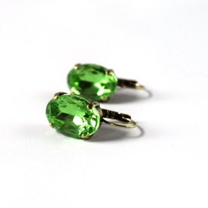 May include: A pair of green oval-shaped earrings with gold-toned metal settings and hooks.