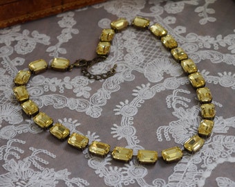 Puede incluir: Un collar de cristal amarillo con una cadena dorada. El collar está hecho de cristales de forma rectangular.