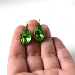 May include: A pair of green oval-shaped earrings with gold-toned metal settings.