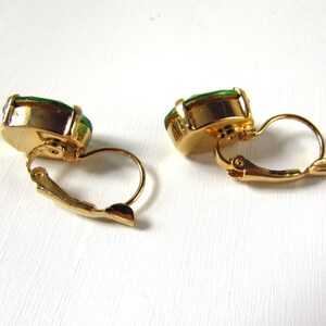 May include: A pair of gold tone clip-on earrings with green oval-shaped stones.