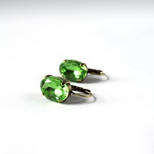 May include: A pair of green oval-shaped earrings with gold-toned metal settings.