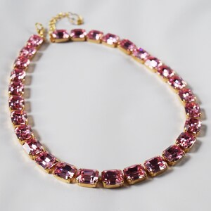 May include: A pink crystal necklace with a gold chain and rectangular-shaped crystals.