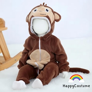May include: A brown baby's monkey costume with a hood shaped like a monkey's face, a tan belly, and a tail. The outfit has a zip and white trim. The HappyCostume logo is visible.