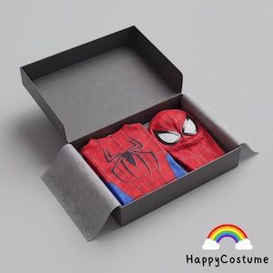May include: A red and blue Spider-Man costume set inside a dark gray rectangular gift box. The set includes a red top with a black spider emblem and a red fabric mask featuring large white eye lenses with black outlines, all neatly packed.