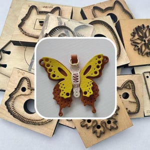 Könnte beinhalten: Ein gelb-brauner Leder-Schmetterling mit einem goldfarbenen Ring, umgeben von Holzwerkzeugen. Der Schmetterling hat eine genähte Mitte und ein detailliertes Flügeldesign. Die Holzwerkzeuge haben verschiedene Formen.
