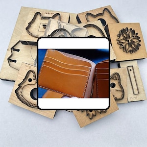 May include: A brown leather wallet with multiple card slots is displayed, surrounded by various wooden die-cut shapes. The die-cuts feature designs like a snowflake, a cat's face, and other geometric forms, suggesting leathercraft tools.